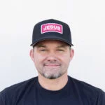 Man wearing the black Warrior Makers classic trucker hat with a pink JESUS patch and a black Warrior Makers t-shirt