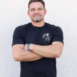 Man with arms crossed wearing the black Warrior Makers t-shirt with the Spartan helmet logo
