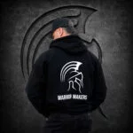 Back view of a man wearing an XXL Warrior Makers black pullover hoodie with white Spartan helmet logo in front of a dark Spartan helmet backdrop