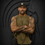 Tattooed man with hands clasped wearing an XXL Warrior Makers green cutoff t-shirt and black hat in front of a dark Spartan helmet backdrop
