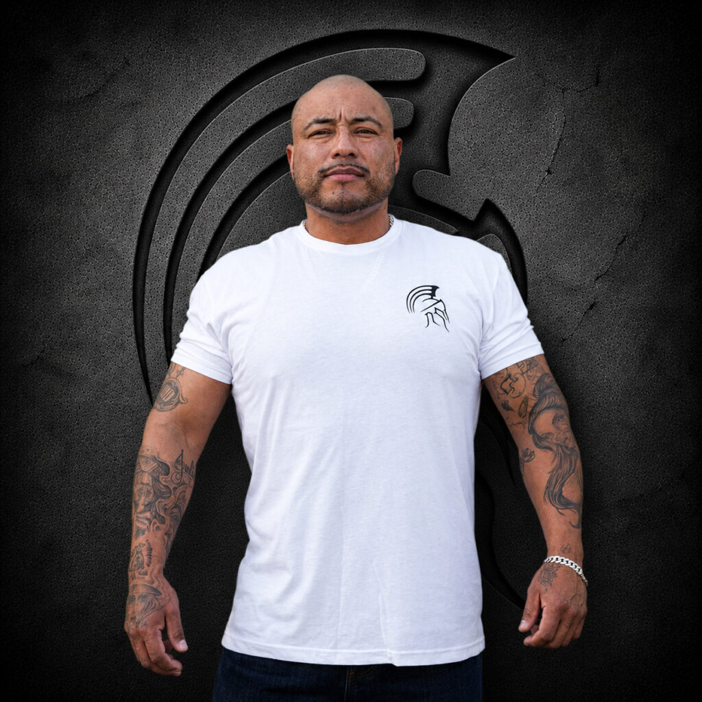 Man wearing an XL Warrior Makers white t-shirt with small chest logo in front of a dark Spartan helmet backdrop