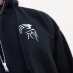 Close-up of the white Spartan helmet logo embroidered on the black Warrior Makers zip hoodie