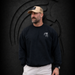 Bearded man wearing an XXL Warrior Makers black crewneck sweatshirt and tan trucker hat in front of a dark Spartan helmet backdrop