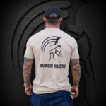 Back view of a man wearing a large Warrior Makers tan t-shirt with black Spartan helmet logo in front of a dark Spartan helmet backdrop