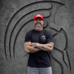 Bearded man in a red cap wearing the black Warrior Makers PEPTIDES t-shirt, front view with Spartan helmet chest logo